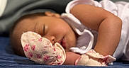 Samantha Lior joined the competition — help win amazing prizes! baby, infant, sleeping, peaceful, portrait, close_up, face, closed_eyes, lying_down, blanket, mittens, floral, clothing, arm, leg, cozy, indoors, soft_lighting, nap, cute