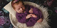 Shiloh is registered to the contest to win money with this photo: newborn, baby, sleeping, purple_outfit, headband, flower, bowl, fluffy, blanket, cozy, infant, portrait, cute, hands, feet, resting, soft, fabric, dark_background, indoors