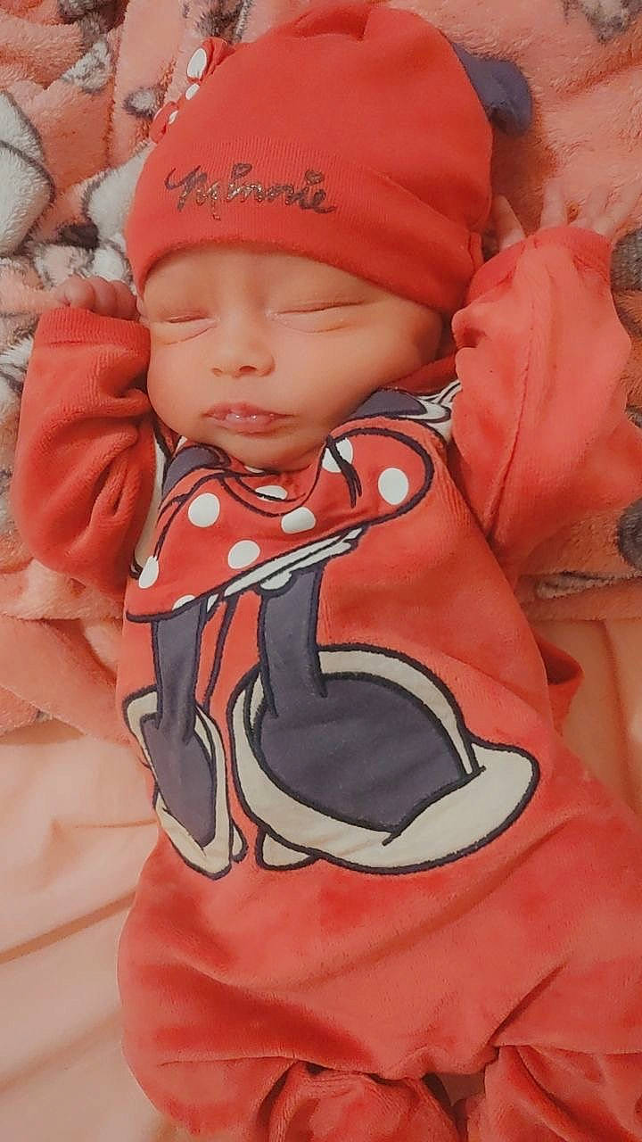 Ryley participe au concours pour gagner de l'argent avec cette photo : arm, baby, baby_carriage, baby_products, baby_toddler_clothing, cap, carmine, child, eye, face, hand, headwear, linens, orange, pattern, peach, person, personal_protective_equipment, pink, sleeve