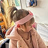 toddler, girl, child, indoor, pink_coat, headband, pony_tail, side_profile, window, natural_light, household_items, wall, clothing, cute, young_child, person, portrait, soft_texture, casual, warm