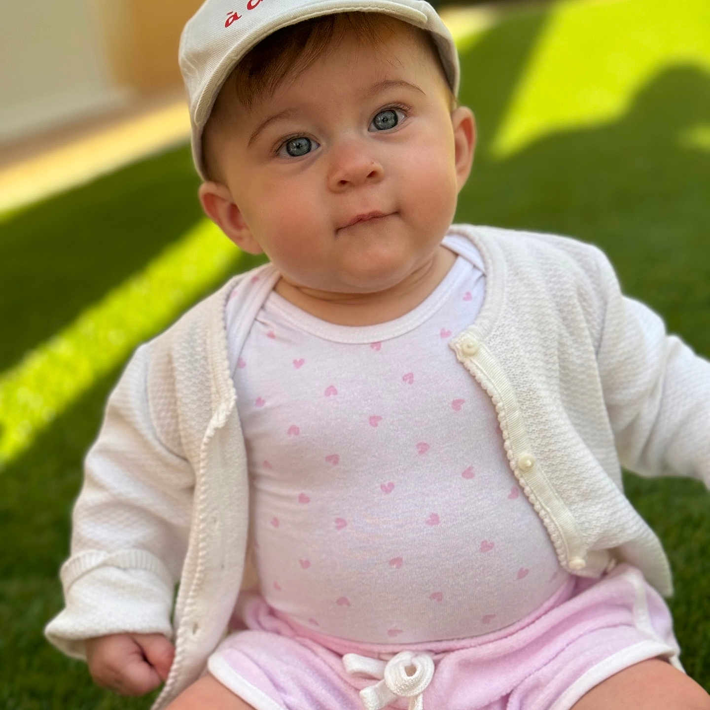 Gioia a rejoint le concours — aidez-le/la à gagner de superbes lots ! baby, baseballcap, cap, clothing, coat, face, grass, hat, head, jacket, knitwear, lawn, person, photography, plant, portrait, shorts, sitting, sweater, t_shirt