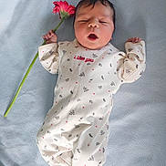 Ayla Boufares participe au concours pour gagner de l'argent avec cette photo : baby, infant, flower, blanket, onesie, sleepy, cute, soft, peaceful, lying_down, hand, pink_flower, patterned_clothing, newborn, cozy, portrait, child, indoor, skin, head