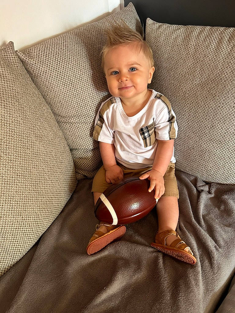 Layan participe au concours pour gagner de l'argent avec cette photo : baby, baby_toddler_clothing, chest, child, comfort, couch, face, flooring, foot, human_leg, joy, knee, person, pillow, sitting, sleeve, smile, t_shirt, thigh, throw_pillow