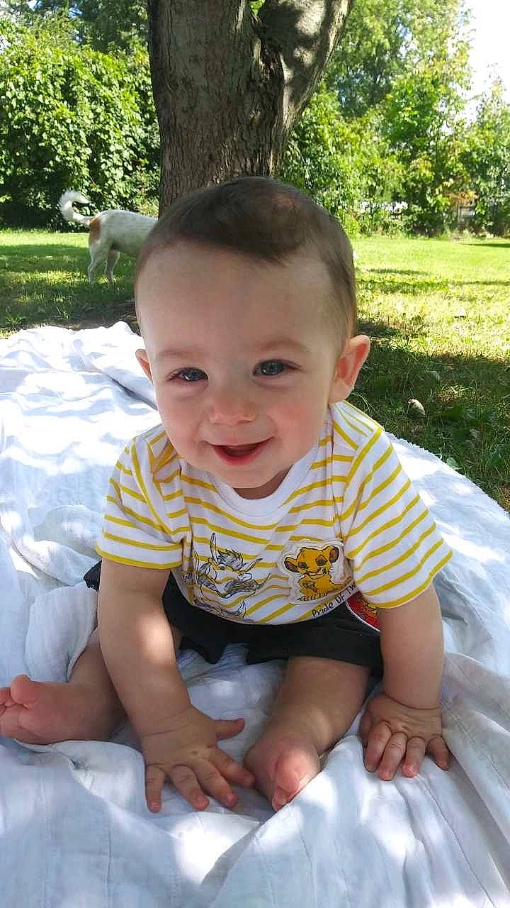 Joey is registered to the contest to win money with this photo: baby, baby_toddler_clothing, botany, eye, facial_expression, finger, grass, green, happy, human_body, joy, leaf, leisure, people_in_nature, person, plant, product, skin, sleeve, smile