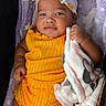 adorable, baby, blanket, bow, bracelet, child, cute, happy, headband, indoors, infant, jewelry, lying_down, necklace, plush_blanket, portrait, purple_blanket, smiling, soft_texture, yellow_outfit