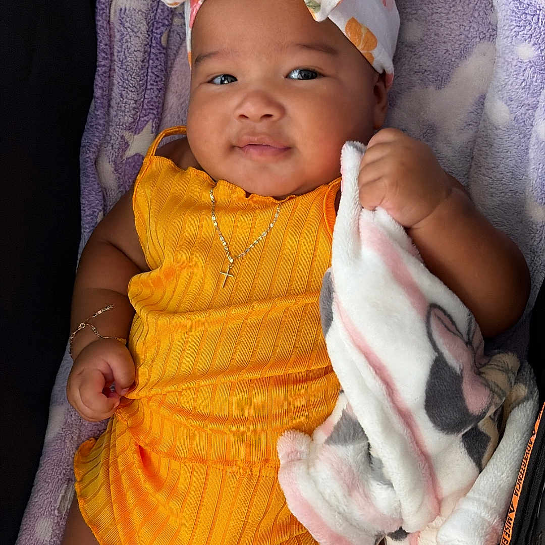 Khalii joined the competition — help win amazing prizes! adorable, baby, blanket, bow, bracelet, child, cute, happy, headband, indoors, infant, jewelry, lying_down, necklace, plush_blanket, portrait, purple_blanket, smiling, soft_texture, yellow_outfit