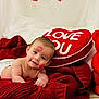 baby, infant, diaper, heart_pillow, red_teddy_bear, roses, kiss_mark, red_blanket, valentine, decorations, smile, lying_down, portrait, plush_toy, cuteness, indoor, photography, soft_texture, love_message, holiday_decor