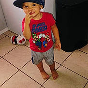 Archie joined the competition — help win amazing prizes! appliance, barefoot, boy, cap, child, cute, happy, indoor, person, playful, plush_toy, red_tshirt, shorts, smiling, standing, super_mario, tile_floor, toddler, toy, trash_bin
