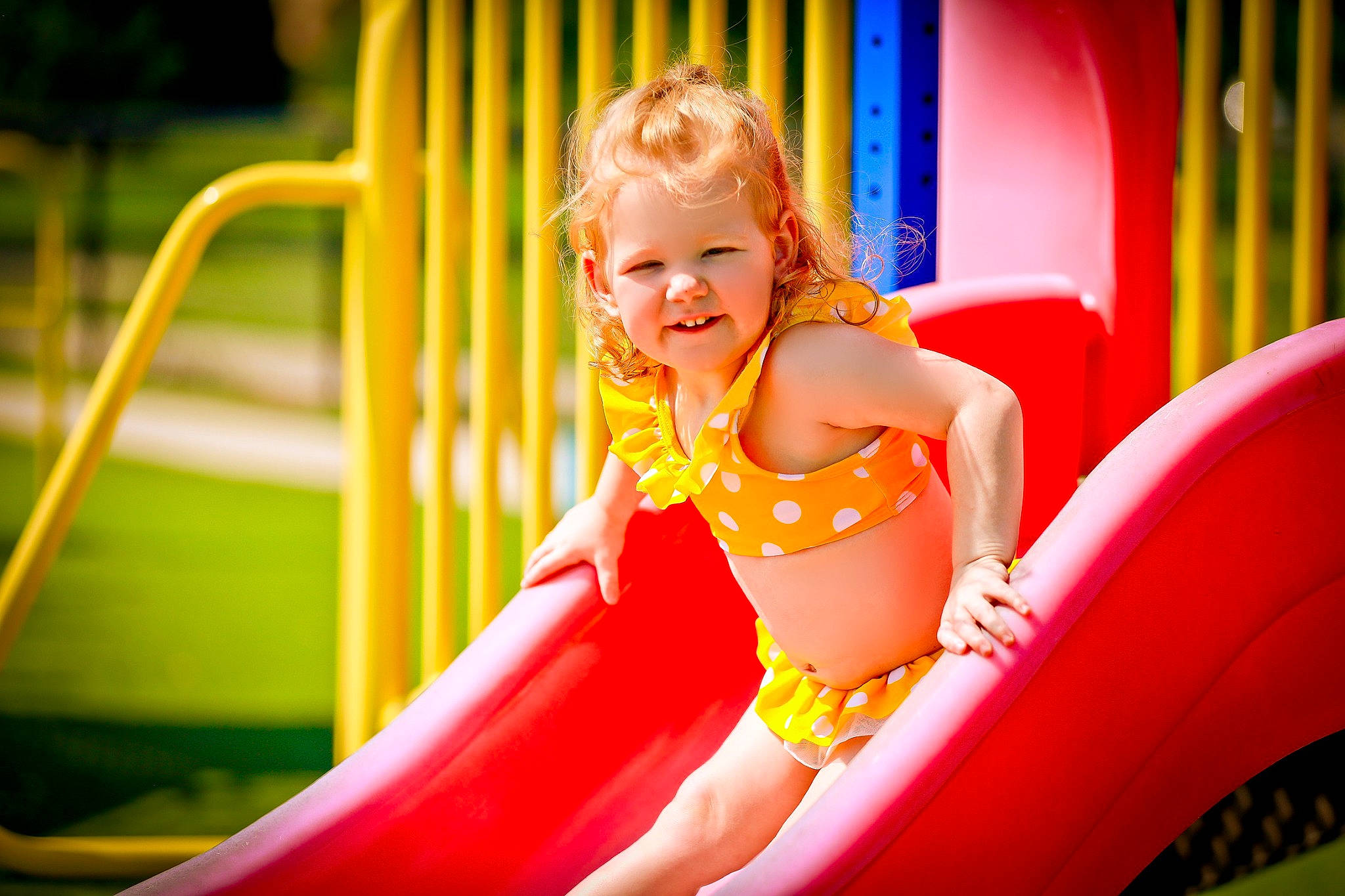 Rowan is registered to the contest to win money with this photo: baby_toddler_clothing, child, chute, city, event, fun, grass, happy, joy, leisure, magenta, outdoor_play_equipment, person, play, playground, playground_slide, public_space, recreation, sitting, skin