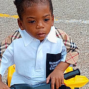 Cassius joined the competition — help win amazing prizes! toddler, child, boy, toy_vehicle, yellow, outdoor, street, clothing, burberry, shorts, hand, face, hair, curly_hair, expression, casual, sitting, handlebars, young_child, fashion