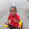 Cassius is registered to the contest to win money with this photo: child, toddler, smiling, red_shirt, sailboat_pattern, toy_vehicle, yellow_toy, outdoor, concrete, waving, happy, person, short_hair, summer, daytime, footwear, play, kid, transport, fun