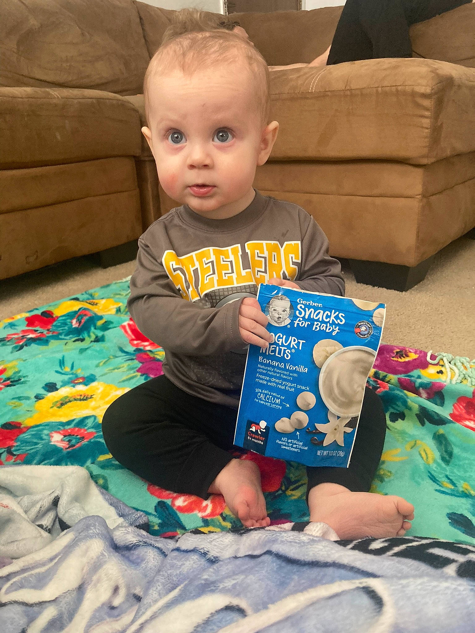 Leighton is registered to the contest to win money with this photo: baby, baby_toddler_clothing, book, child, comfort, couch, flooring, fun, holiday, lap, living_room, person, play, product, room, sitting, summer, surprise, t_shirt, textile