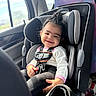 toddler, child, baby, smiling, happy, car, car_seat, seatbelt,  안전, passenger, indoors, vehicle, portrait, curly_hair, hair_bun, pink_clothing, white_shirt, black_pants, sunlight, road_trip