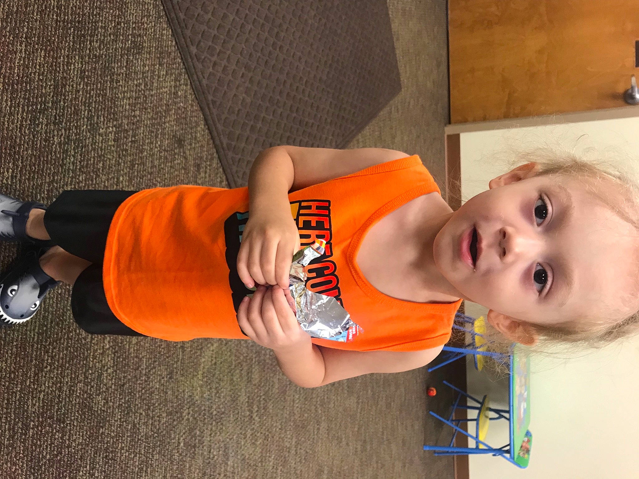 James is registered to the contest to win money with this photo: abdomen, baby, child, elbow, finger, fun, hat, human_leg, joint, knee, orange, person, room, sleeve, smile, sportswear, t_shirt, thigh, toddler, trunk