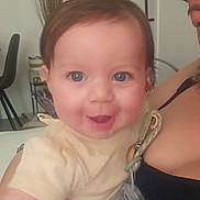 Léa-Rose participe au concours pour gagner de l'argent avec cette photo : adult, baby, blue_eyes, candid, chair, child, closeup, face, furniture, happy, holding, home, indoor, pacifier, person, plant, portrait, shirt, skin, smiling