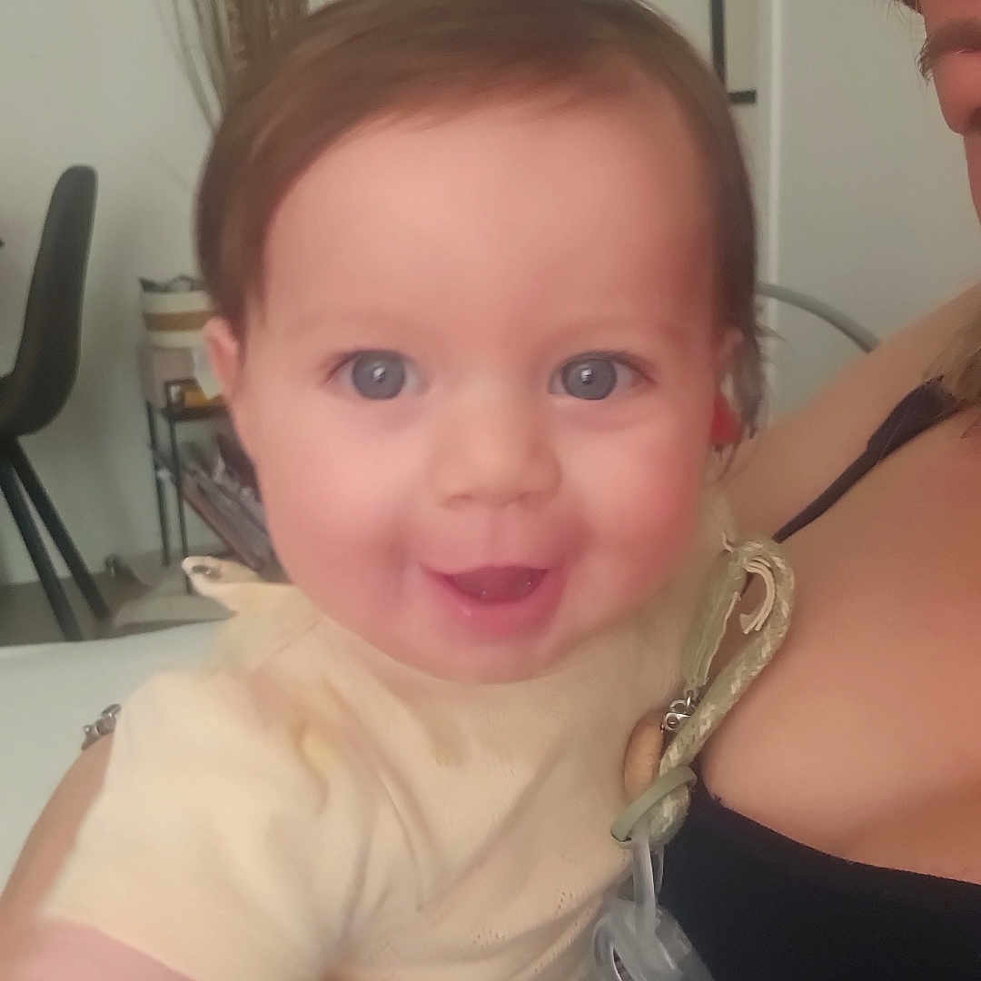 Léa-Rose participe au concours pour gagner de l'argent avec cette photo : adult, baby, blue_eyes, candid, chair, child, closeup, face, furniture, happy, holding, home, indoor, pacifier, person, plant, portrait, shirt, skin, smiling