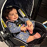 Abigail is registered to the contest to win money with this photo: baby, child, stroller, pajamas, foot, hand, face, seatbelt, indoor, warning_label, curly_hair, cute, infant, grabbing, child_seat, toy, black_stroller, expression, comfort, casual