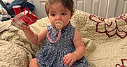 Abigail is registered to the contest to win money with this photo: baby, child, pacifier, blue_dress, quilt, blanket, indoor, sitting, holding, carton, foot, hand, face, hair, room, door, furniture, cozy, cute, infant