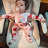 baby, child, pacifier, pajamas, chair, indoor, floor_tile, footwear, slipper, wood_furniture, looking_away, long_sleeves, cute, comfort, home, infant, seated, expression, person, face