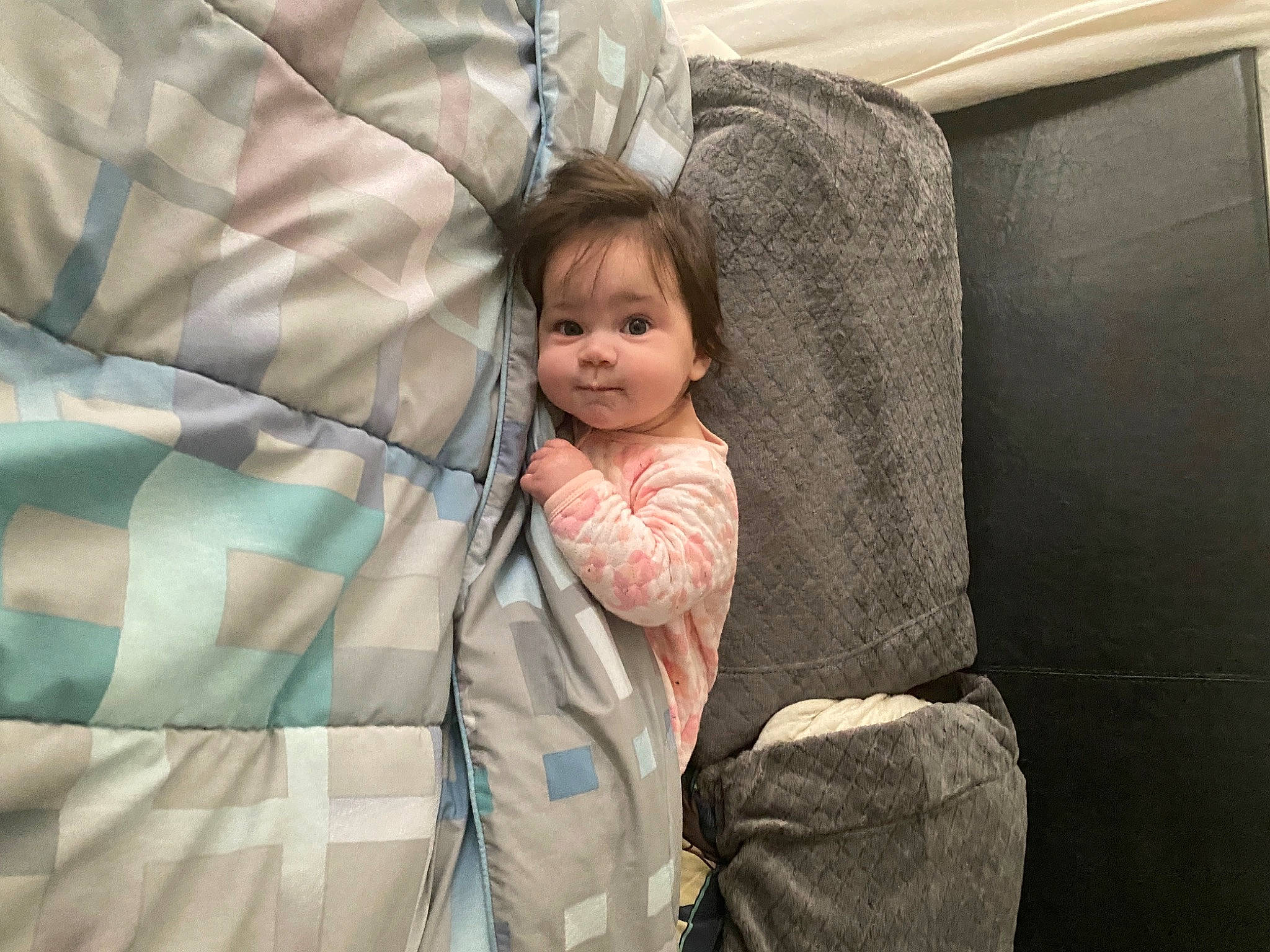 Emma is registered to the contest to win money with this photo: baby, baby_products, child, comfort, couch, face, fun, head, leisure, linens, luggage_and_bags, luxury_vehicle, pattern, person, room, sitting, textile, throw_pillow, toddler, travel