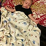 Elias is registered to the contest to win money with this photo: baby, blanket, pillow, sleeping, child, indoor, cozy, patterned, bed, resting, toddler, young_child, comfort, soft, person, clothing, head, face, lying_down, relaxed