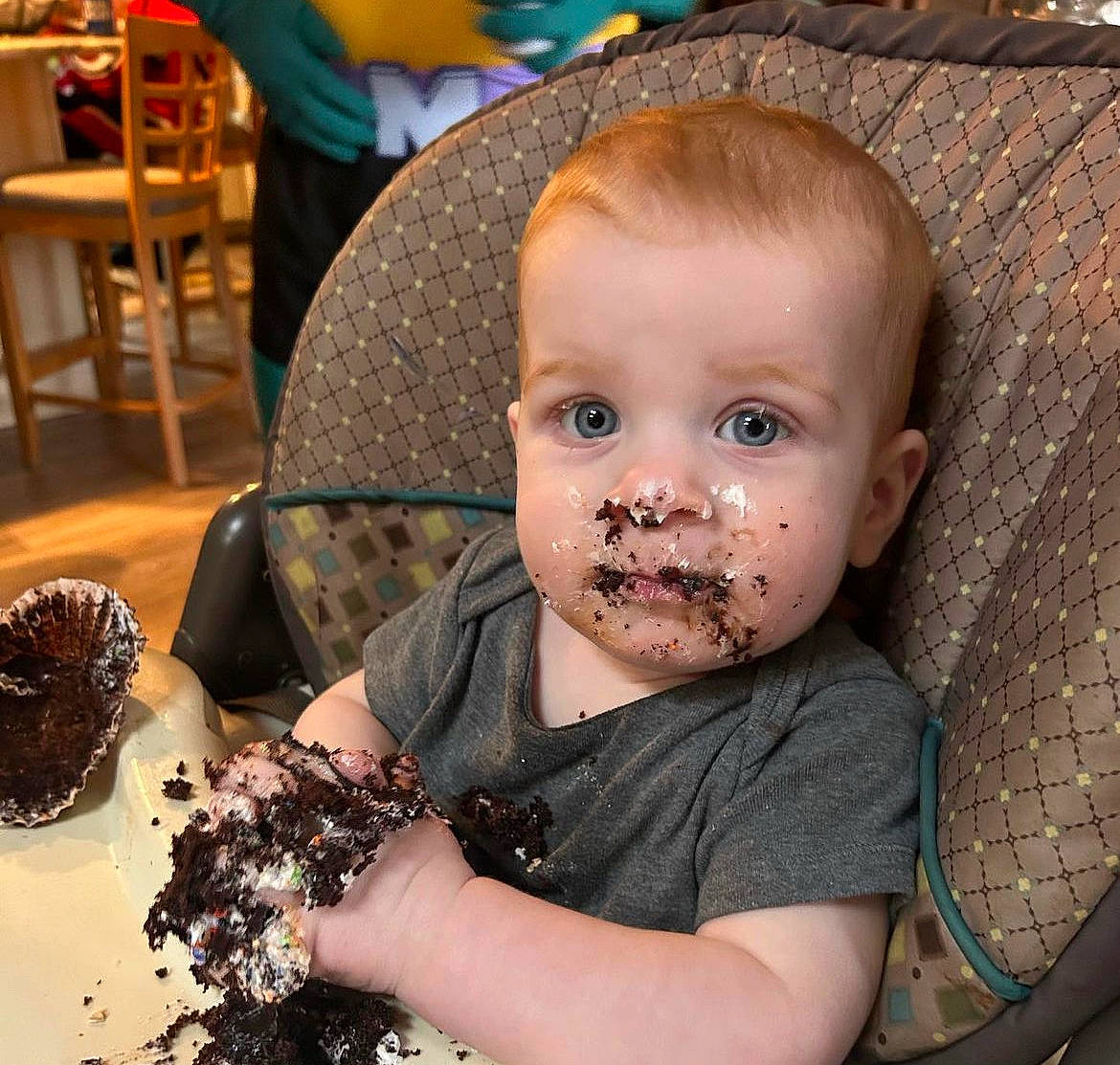 Kamden is registered to the contest to win money with this photo: baby, baking, birthday_cake, cake, chair, cheek, child, comfort_food, dessert, fashion_accessory, food, fun, head, icing, pastry, person, plate, sitting, sweetness, tableware