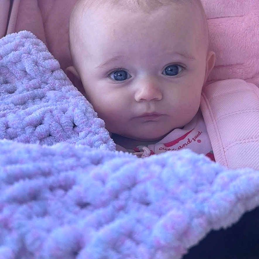 Delilah is registered to the contest to win money with this photo: baby, blanket, child, clothing, cozy, cute, expression, face, head, indoors, infant, newborn, pink, plush, portrait, purple, soft, warm, wrapped, young