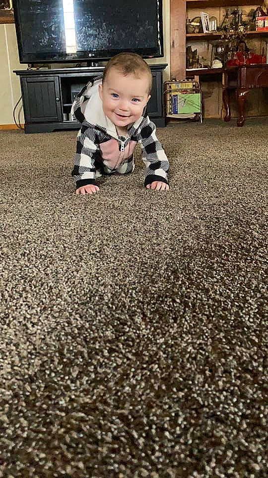 Alaska is registered to the contest to win money with this photo: asphalt, baby, baby_toddler_clothing, black, carpet, child, crawling, floor, flooring, grass, hardwood, joy, people, people_in_nature, person, road_surface, smile, soil, standing, toddler