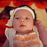 Hazel is registered to the contest to win money with this photo: baby, infant, headband, white_clothing, orange_clothing, blanket, red, orange, face, portrait, child, cute, lying_down, newborn, skin, hand, expression, indoors, soft_texture, young