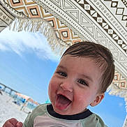 Arian is registered to the contest to win money with this photo: child, toddler, smiling, tongue_out, beach, umbrella, sunny, blue_sky, patterned_umbrella, happy, wet_hair, outdoor, summer, playful, close_up, face, person, vacation, fun, casual_clothing