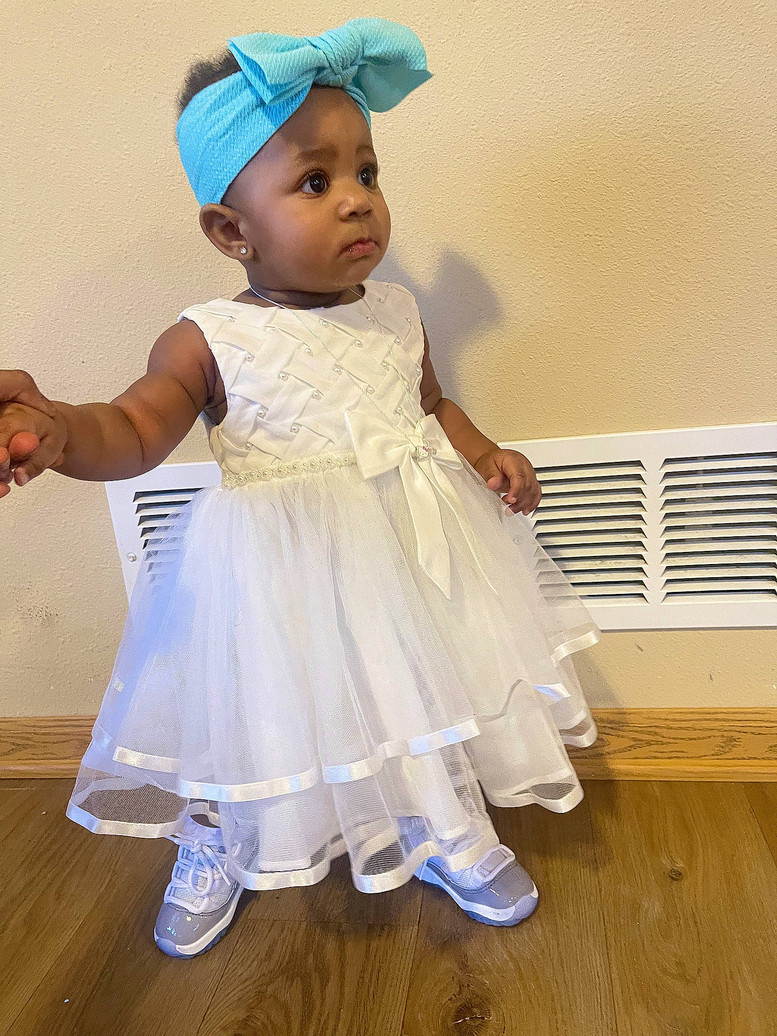 Kior is registered to the contest to win money with this photo: baby, baby_toddler_clothing, cap, child, day_dress, fashion_accessory, flooring, fun, gesture, happy, hardwood, hat, headgear, headpiece, human_leg, person, sitting, sleeve, toddler, white