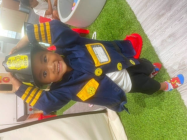 Hercules is registered to the contest to win money with this photo: child, fictional_character, flooring, fun, hat, headwear, joy, leisure, person, personal_protective_equipment, recreation, room, smile, sportswear, t_shirt, toddler