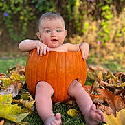 Aaron is registered to the contest to win money with this photo: baby, pumpkin, autumn_leaves, grass, outdoor, child, fall, cute, nature, seasonal, smiling, portrait, leaf, orange, green, skin, sitting, playful, holiday, baby_face