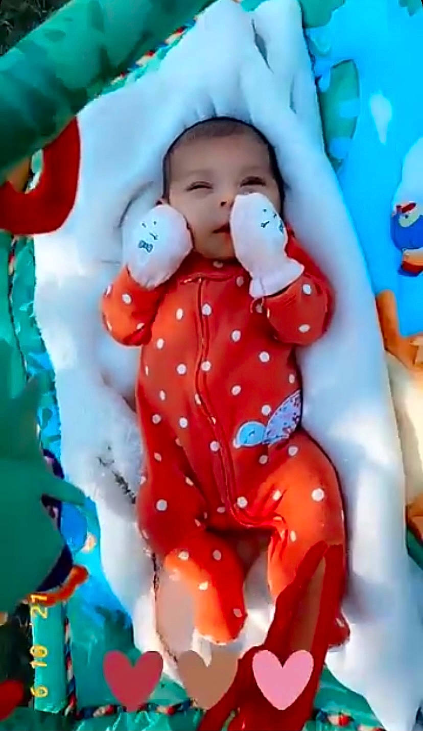 Amina is registered to the contest to win money with this photo: baby, baby_toddler_clothing, blue, carmine, child, christmas, event, fictional_character, fun, gesture, happy, holiday, party_supply, pattern, person, pink, sleeve, smile, stuffed_toy, textile