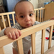 Léo a rejoint le concours — aidez-le/la à gagner de superbes lots ! baby, crib, hand, furniture, room, indoor, child, person, curious, standing, striped_clothing, wood, floor, door, cabinet, toy, home, expression, face, young