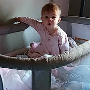 Ashlynn is registered to the contest to win money with this photo: baby, child, playpen, pajamas, blanket, toy, indoor, curious, expression, face, person, furniture, soft, sleepwear, home, childcare, infant, cute, young, standing