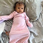 Violet is registered to the contest to win money with this photo: baby, infant, pink_onesie, headband, pacifier, bed, gray_bedspread, lying_down, looking_at_camera, curious, soft_lighting, indoors, child, small_hands, cute, sleepwear, blanket, comfortable, portrait, young_child