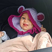 Aria a rejoint le concours — aidez-le/la à gagner de superbes lots ! baby, blanket, car_seat, child, clothing, cozy, cute, face, happy, headwear, indoors, infant, knitted_hat, magenta, person, portrait, purple, smiling, tongue_out, warm