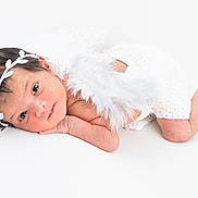 Rysa is registered to the contest to win money with this photo: newborn, baby, infant, headband, feathers, white_background, cute, portrait, lying_down, soft_texture, peaceful, small, child, skin, face, eyes, hand, legs, white_clothing, studio_photo