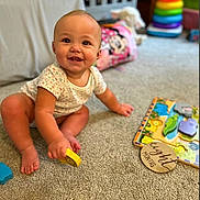 Ally joined the competition — help win amazing prizes! baby, child, smiling, sitting, carpet, toy, puzzle, wooden_plaque, crib, nursery, indoor, colorful, playtime, infant, clothing, floor, person, happy, cute, room