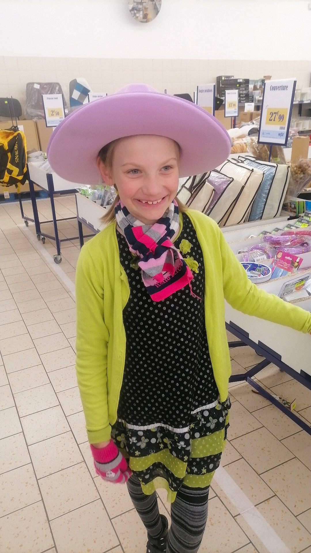 Louanna participe au concours pour gagner de l'argent avec cette photo : bookcase, child, costume_hat, event, face, fashion_accessory, fashion_design, formal_wear, fun, happy, hat, headgear, headwear, joy, pattern, person, purple, scarf, shelf, sleeve