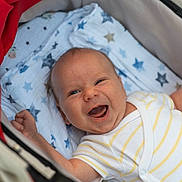 Aleks participe au concours pour gagner de l'argent avec cette photo : baby, infant, smiling, happy, blanket, stars, stroller, clothing, white, yellow_stripes, face, skin, hands, cute, joyful, lying_down, closeup, child, newborn, portrait