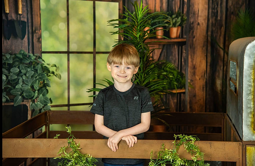 Gabriel is registered to the contest to win money with this photo: annual_plant, flowerpot, fun, garden, grass, happy, herb, houseplant, joy, leaf, leisure, person, plant, shorts, sitting, smile, t_shirt, terrestrial_plant, toddler, window