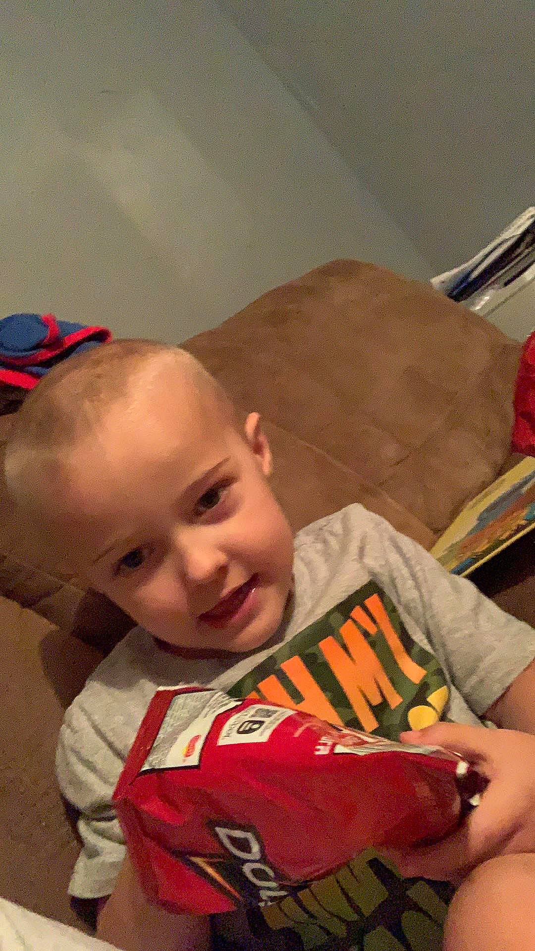 Cody is registered to the contest to win money with this photo: baby, carmine, cheek, child, christmas, comfort, fun, happy, holiday, junk_food, lap, laugh, mouth, orange, person, personal_protective_equipment, play, room, sitting, smile