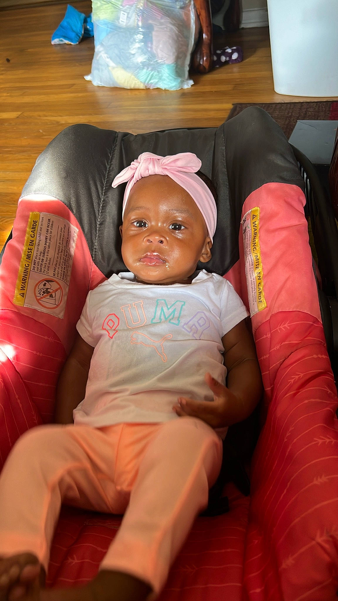 Kayani joined the competition — help win amazing prizes! baby, baby_toddler_clothing, cap, car_seat, chair, comfort, couch, fun, furniture, human_leg, lap, linens, living_room, person, pillow, pink, room, sitting, thigh, throw_pillow