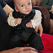 Dario a rejoint le concours — aidez-le/la à gagner de superbes lots ! baby, tuxedo, bow_tie, person, hand, indoor, couch, clothing, child, portrait, sitting, cute, face, infant, adult_hand, home, fashion, black_clothing, white_shirt, footwear