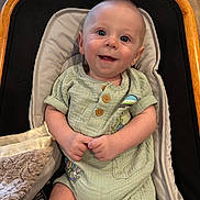 Ryland is registered to the contest to win money with this photo: baby, infant, child, smile, happy, face, clothing, romper, seat, baby_seat, cushion, wood_floor, wood_frame, indoor, portrait, cute, sitting, hand, skin, eyes