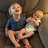 child, baby, sibling, couch, furniture, smiling, happy, indoor, person, cute, toddler, sitting, casual_clothing, barefoot, blond_hair, infant, relaxing, family, playful, portrait