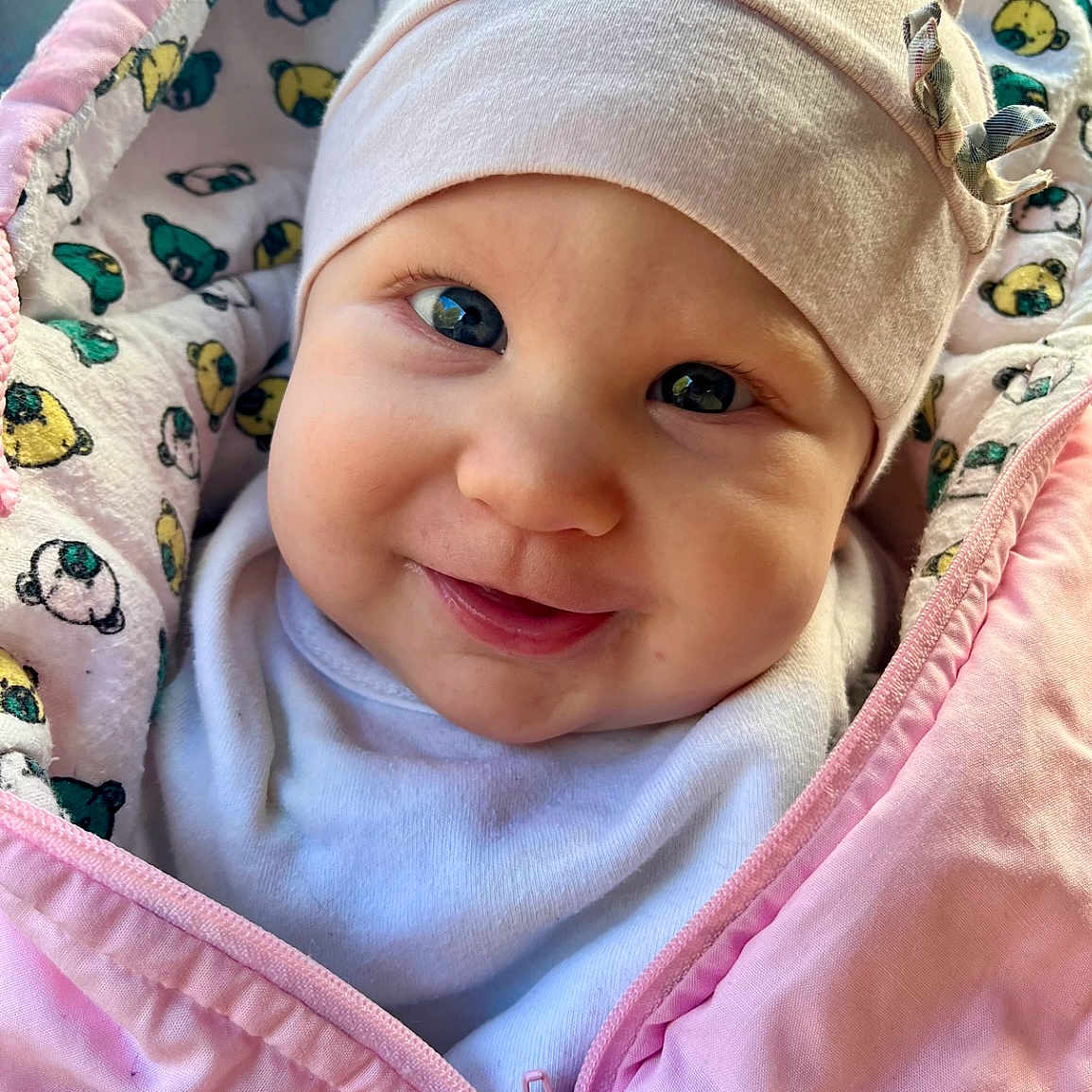 Gianna participe au concours pour gagner de l'argent avec cette photo : apparel, baby, baby_face, blanket, bow, child, close_up, cozy, cute, face, happy, hat, indoors, infant, person, pink_jacket, portrait, smiling, soft_texture, warm_clothing