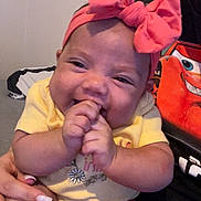 Addelyn joined the competition — help win amazing prizes! baby, smiling, pink_bow, yellow_onesie, hands, person_holding, manicured_nails, indoor, clothing, cute, happy, child, face, headband, infant, people, portrait, skin, expression, sitting